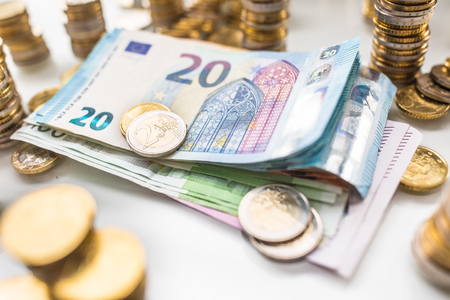 Euro banknotes and coins togetger on white table - close-up.の写真素材