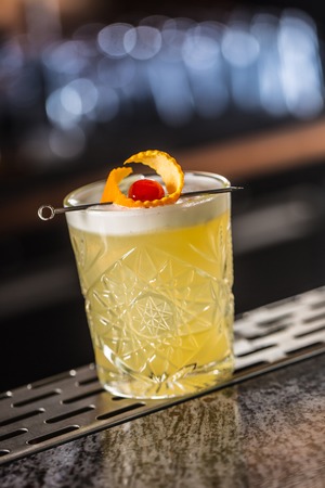 Cocktail drink whiskey sour at barcounter in night club or restaurant.