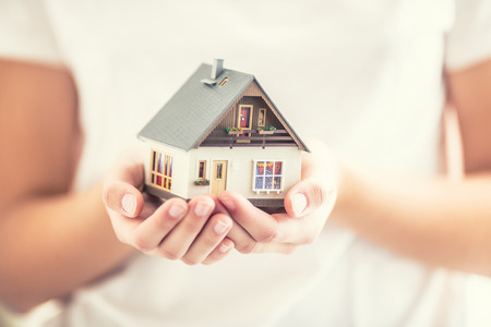 Hands of young woman holding model house.の写真素材