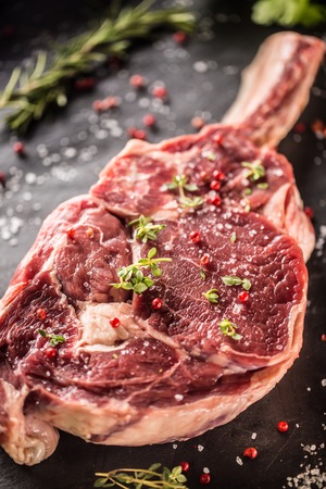 Raw beef tomahawk steak with salt pepper and rosemary on slate plate.の写真素材