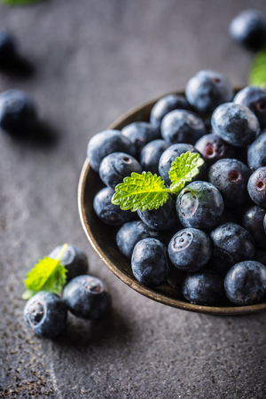 Vintage bowl full of fresh blueberries with herbs.の写真素材