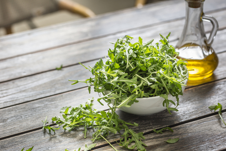 Fresh arugula salad with olive oil  in white dish on wooden table.の写真素材