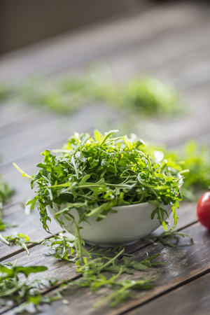 Fresh arugula salad in white dish on wooden table.の写真素材