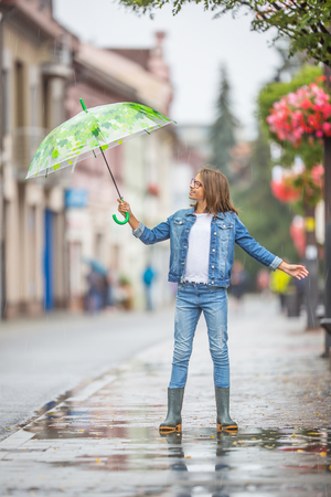 Portrait of beautiful young pre-teen girl with umbrella under spring or summer rain.の写真素材