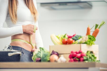 Woman waist with measuring tape over wooden box with vegetable.の写真素材