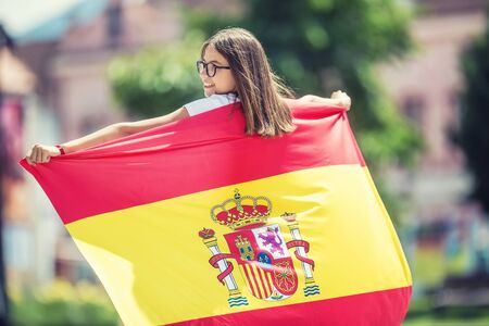 Happy girl tourist walking in the street with spanish flag.の写真素材