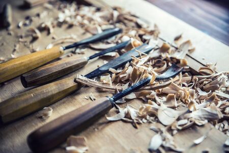 Woodworking vintage tools chisels with wood shawings on retro workbench.の写真素材
