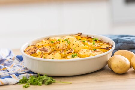 Roasted potatoes with spices and herbs on kitchen table.の写真素材