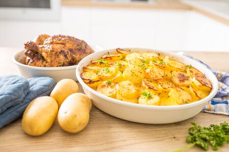 Traditional meal roasted potatoes and whole chicken on home kitchen table.の写真素材