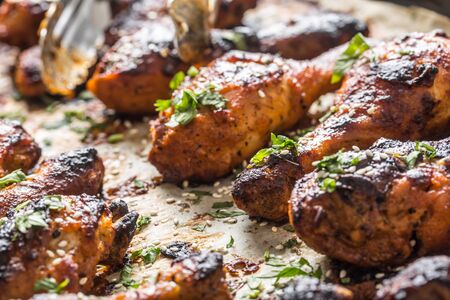 Grilled hicken legs BBQ with spices herbs and sesame on baked paper. Roasted poultry meal in roaster...