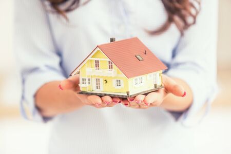 Hands of young woman holding model house.の写真素材