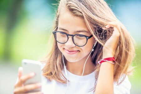 Young teenage girl with headphones enjoying with good music. Modern young woman with cellphone.の写真素材