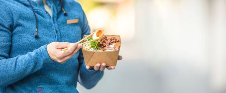 Young mans hands holding lunch in a box of recycled paper.