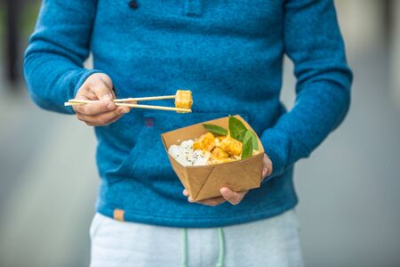 Young mans hands holding lunch in a box of recycled paper.の写真素材