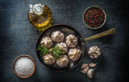 Garlic cloves and bulb in pan with fresh rosemary olive oil salt and spice on concrete table - Top of view.の写真素材