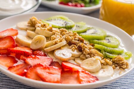Healthy breakfast served with plate of yogurt muesli kiwi strawberries and banana. Morning table...