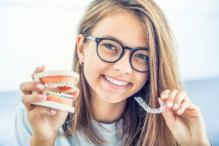 Dental invisible braces or silicone trainer in the hands of a young smiling girl. Orthodontic concept - Invisalign.の写真素材