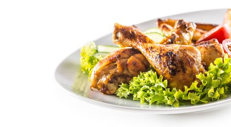 Roasted chicken legs with lettuce salad potatoes and tomatoes isolated on white.の写真素材