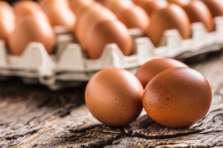 Chicken eggs in carton box on rustic wooden table.