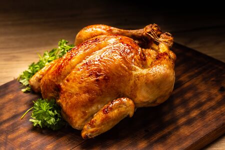 Roasted whole chicken on wooden cutting board.の写真素材