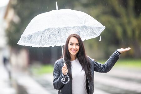 Smiling pretty girls with an umbrella checks with her hand, whether it is still raining.の写真素材