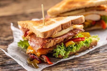 Club sandwich on a rustic table witch chicken, bacon, pepper and lettuce.の写真素材