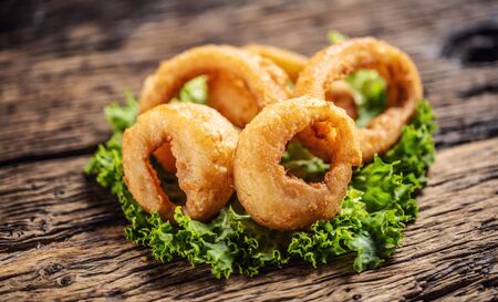 Cripsy onion rings on a lettuce leaf placed on a rustic wood.の写真素材