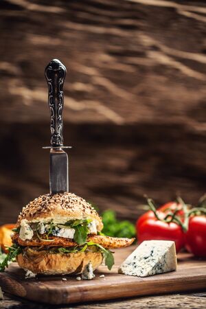 Chicken burger with blue cheese and arugula in a sesame bun on a rustic wood.の写真素材