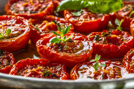 Roasted tomatoes with olive oil thyme oregano and basil in pan.