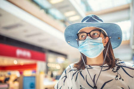 Young woman is protected from coronavirus with a protective mask in the interior of the supermarket.の写真素材
