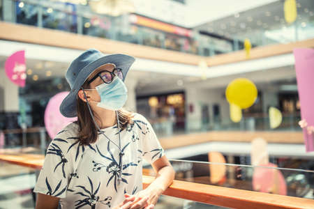 Young woman is protected from coronavirus with a protective mask in the interior of the supermarket.の写真素材