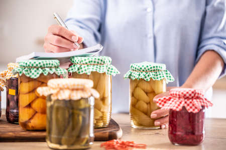 Woman looking at fresh home-made preserves in her hands with more pickles in jars in front of her.の写真素材