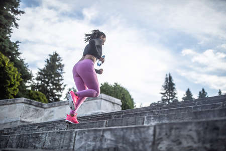 Young woman doing sports and running up the stairs.