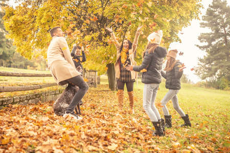 Autumn fun for a family with children outdoors in colorful yellow and orange leaves.
