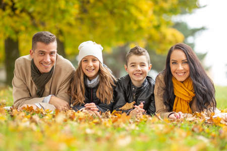 Happy family lying on a blanket outdoors on a beautiful autumn day.の写真素材