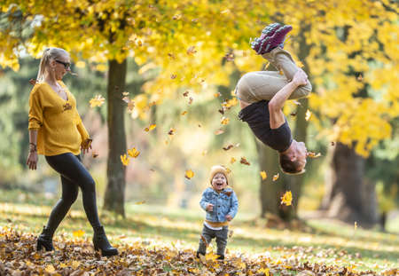 Dad doing backflip makes his son and wife laugh during a fun autumn day in teh nature.の写真素材