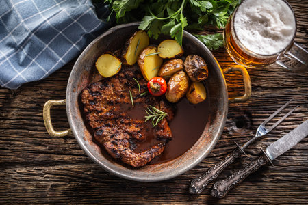 Top view of baked pork nech with potaties served in metallic vintage bowl and beer.の写真素材