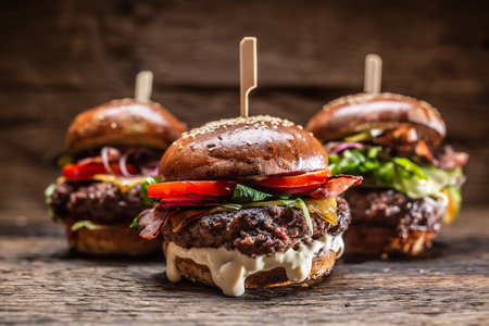 Assortment of three various burgers ready to be plated, with a dark wooden background.の写真素材