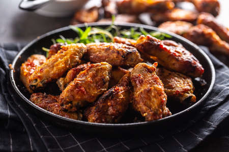 Chicken wings barbeque in a cast iron baking dish with BBQ sauce and rosemary.の写真素材