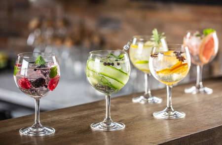 Gin tonic long drink as a classic cocktail in various forms with garnish in individual glasses such as orange, lemon, grapefruit, cucumber or berries.の写真素材