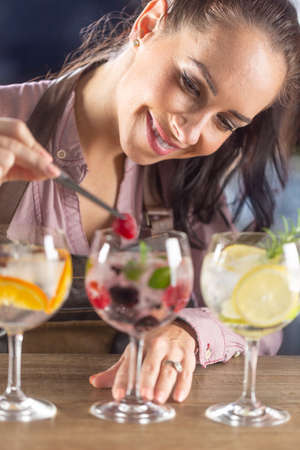 Detail of a barmaid doing finishing touches of cocktail decoration in a bar.