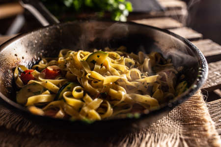 Vegetarian tagliatelle with zucchini and tomatoes served in sizzling hot pan.の写真素材