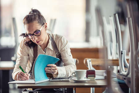 Restaurant owner does bills and paperwork after hours over coffee.