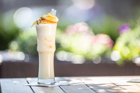 Pinacolada or Milkshake cocktail with straws and orange on top served in a high glass on a summer terrace.の写真素材