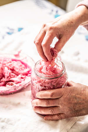 Old granny putting sour cabbage from jar into glass bowl.の写真素材