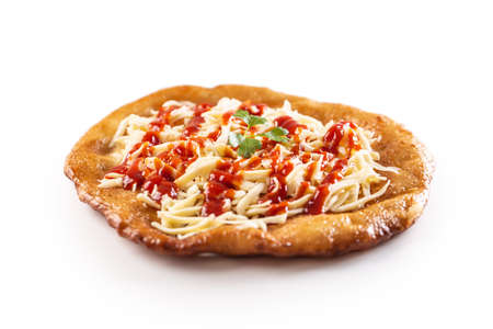 Tasty hungarian langos served with sour creme, ham, cheese, herbs and vegetables in the background.
