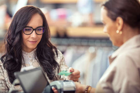 Female customer using contactless card payment for ther clothes in the shop.