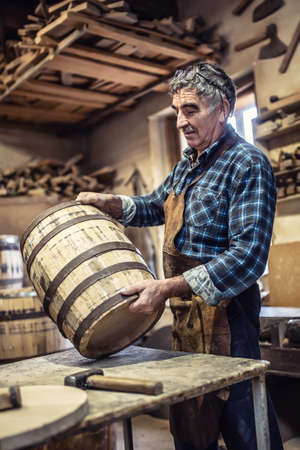 Wooden barrels producer evaluates the quality of finished product in his hands.の写真素材