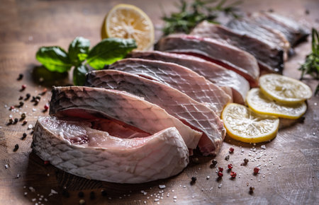 Portioned fish carp with salt pepper lemon and herbs on kitchen board.の写真素材