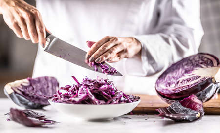 Chef takes remaining bits of cut red cabbage from a knife into a bowl.の写真素材